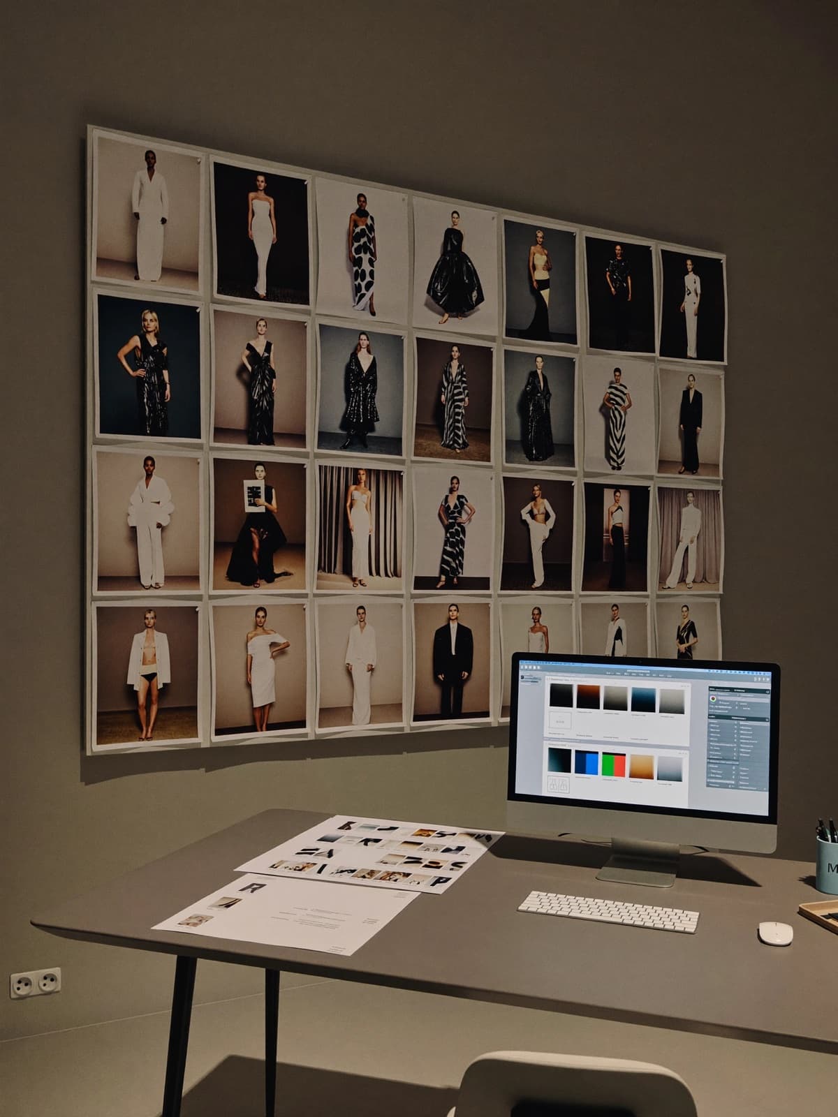 Studio wall of campaign prints beside a working desk