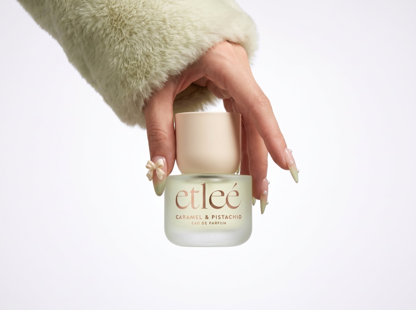 Hand holding a frosted eau de parfum bottle against a white backdrop